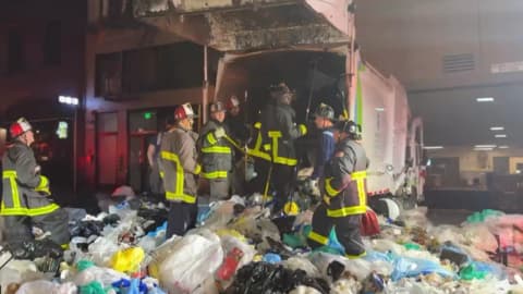 Bystander heard screams from a compacted garbage truck; 25 firefighters rescued a trapped man alive